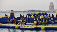 Wisatawan baik anak-anak maupun orang dewasa nampak asyik bermain wahana air di pantai. 