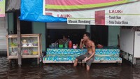 Seorang warga duduk di depan warung makan yang terendam banjir di Jalan Mendawai Induk, Palangka Raya, Kalimantan Tengah, Kamis (17/11/2022). 