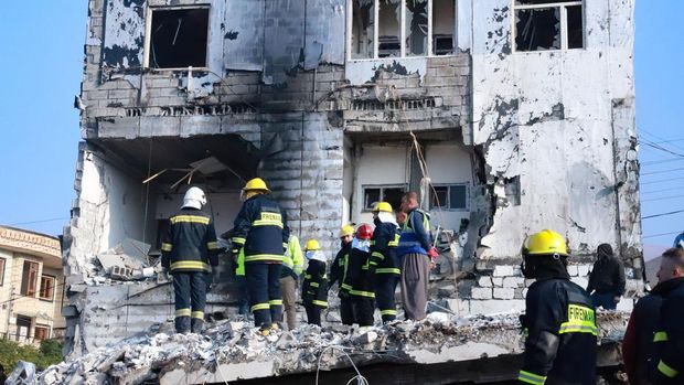 People gather as firefighters search for victims and survivors under the rubble of a building which collapsed after gas tank exploded, in the northern Iraqi city of Suleimaniyah, on November 18, 2022. - The search for victims trapped under the rubble continues, after at least 11 people were killed, local authorities said. (Photo by Shwan MOHAMMED / AFP) (Photo by SHWAN MOHAMMED/AFP via Getty Images)