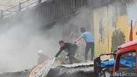 Ada sejumlah orang tak berseragam damkar yang ikut membantu proses pemadaman api. Mereka turut membantu pembongkaran dinding seng di lokasi kios yang terbakar (Indah Mutiara Kami/detikcom)
