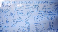 Para siswa menggalang tanda tangan menolak relokasi di sebuah whiteboard.