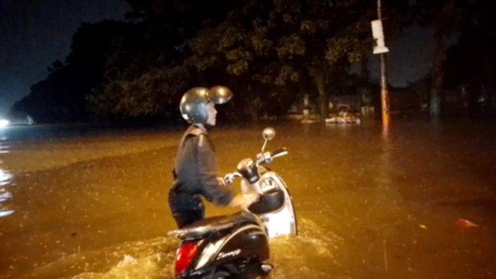 Seorang pengendara turun dari sepeda motor akibat mongok di tengah banjir dan guyuran hujan di Medan. Farid Achyadi Siregar/detikSumut