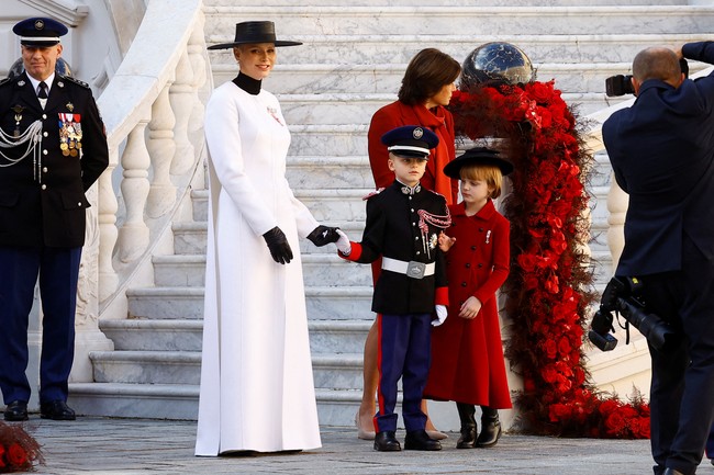 Putri Charlene dan anak perempuannya tampil kompak dengan busana yang merepresentasikan warna bendera Monako. Seperti Indonesia, negara kecil di barat Eropa ini memiliki bendera berwarna merah di bagian atas dan putih di bawah. (Foto: POOL/AFP via Getty Images/ERIC GAILLARD)