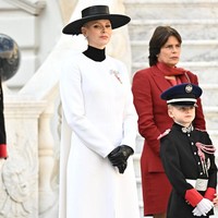 Putri Charlene menebar pesonanya dalam balutan gaun putih keluaran label Akris yang dilengkapi cape panjang dan turtleneck hitam. Tidak ketinggalan sarung tangan dan topi broad-brimmed senada yang elegan. (Foto: David Niviere/SC Pool via Getty Images)