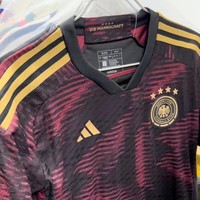 Jersey tandang Jerman terlihat cukup stylish dan unik dengan perpaduan warna hitam dan merah muda keunguan. Bagian pundaknya dihiasi dengan 3 garis berwarna emas. Senada dengan warna garis pada bagian pundaknya, logo Adidas dan sepak bola Jerman di bagian dada juga berwarna keemasan. Foto: Twitter/@Soccerdealshop1