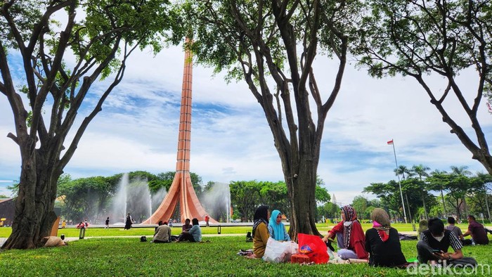 Pengunjung menikmati suasana taman  dan angin sepoi sepoi yang sejuk di kawasan TMII, Jakarta, Minggu (20/11/2022).