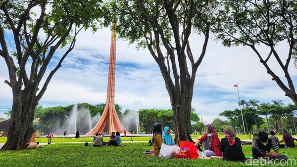 Pengunjung menikmati suasana taman  dan angin sepoi sepoi yang sejuk di kawasan TMII, Jakarta, Minggu (20/11/2022).  