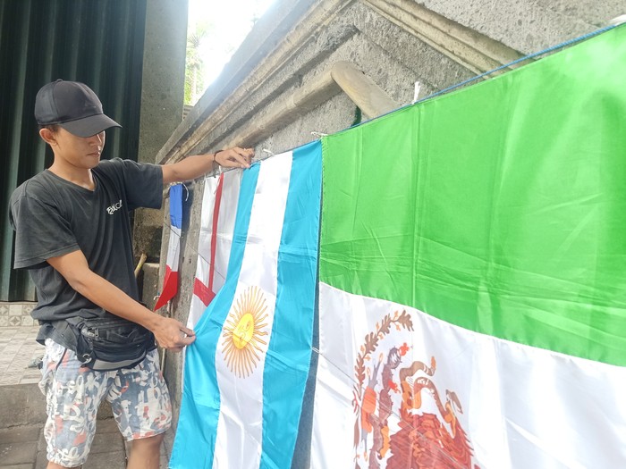 Pedagang bendera, Billy Muhammad Bilar (26) ketika tengah merapikan bendera-bendera yang Ia jual pada Minggu (20/11/2022) di di kawasan Jalan WR. Supratman, Denpasar, Bali. Foto: Ni Made Lastri Karsiani Putri