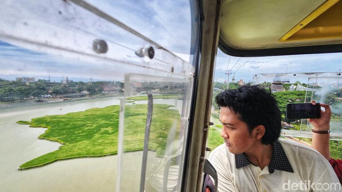 Pengunjung TMII melihat pemandangan atas dari dalam wahana kereta gantung di TMII, Jakarta Timur, Minggu (20/11/2022).