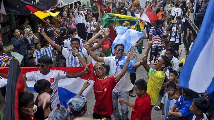 Soccer fans wave the flags of participating countries during a parade ahead of the kick-off of the Qatar FIFA World Cup, in Pambusuang village, West Sulawesi, Indonesia, Sunday, Nov. 20, 2022. Qatar prepared Sunday to open the Middle Easts first FIFA World Cup before global leaders and soccer fans now pouring into this energy-rich nation after being battered by a regional boycott and international criticism. (AP Photo/Yusuf Wahil)