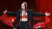 Aksi panggung Dove Cameron yang memadukan blazer hitam dan merah. Foto: Getty Images/Kevin Winter
