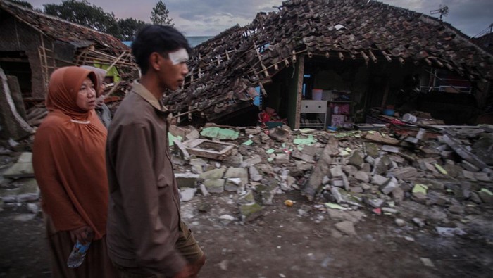 Warga melintas di depan rumahnya yang rusak akibat gempa di Desa Cibeureum, Kabupaten Cianjur, Jawa Barat, Senin (21/11/2022). Gempa bumi berkekuatan 5,6 magnitudo yang mengguncang Kabupaten Cianjur menyebabkan ratusan rumah di kawasan tersebut mengalami kerusakan. ANTARA FOTO/Yulius Satria Wijaya/tom.