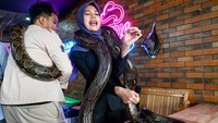 Ekspresi pengunjung wanita saat menggendong ular sanca.