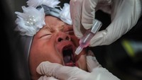 Seorang anak yang menangis saat diberikan imunisasi polio oleh tenaga kesehatan.