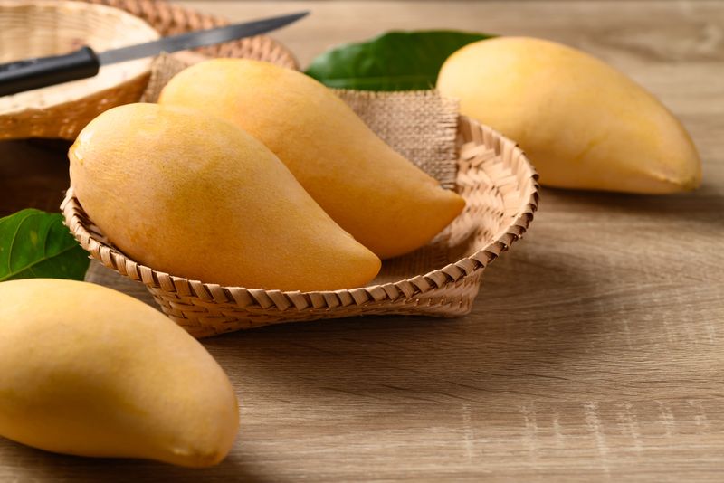 Thai mango fruit (Nam Dok Mai) in basket on wooden background, Tropical fruit in summer season