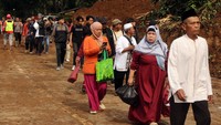 Sejumlah warga melintas di jalan yang telah dibersihkan dari material longsor akibat gempa di Jalan Raya Puncak-Cianjur, Cugenang.  