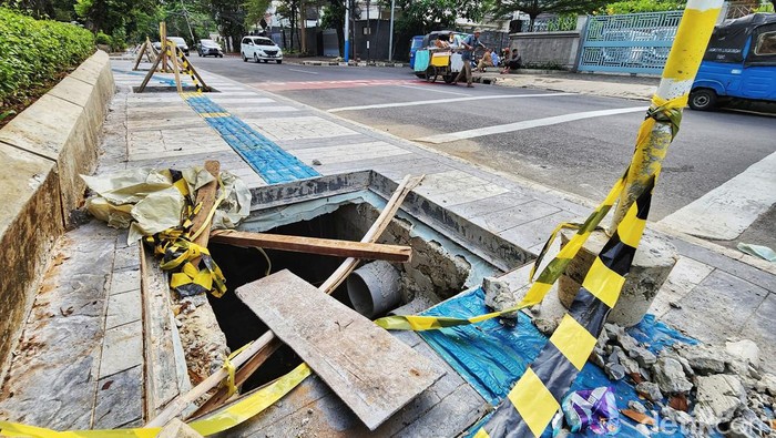 Warga melintas di jalur pedestrian dengan got yang belum ditutup dan hanya diberi penanda kayu di Jalan Agus Saloim, Jakarta Pusat, Selasa (22/11/2022). Proyek perbaikan trotoar yang masih menyisakan tutup got ini sudah berlangsung sejak beberapa hari lalu. Warga berharap got segera ditutup untuk keamanan dan kenyamanan pengguna jalur pedestrian. Foto diambil sekitar pukul 16.00 WIB.