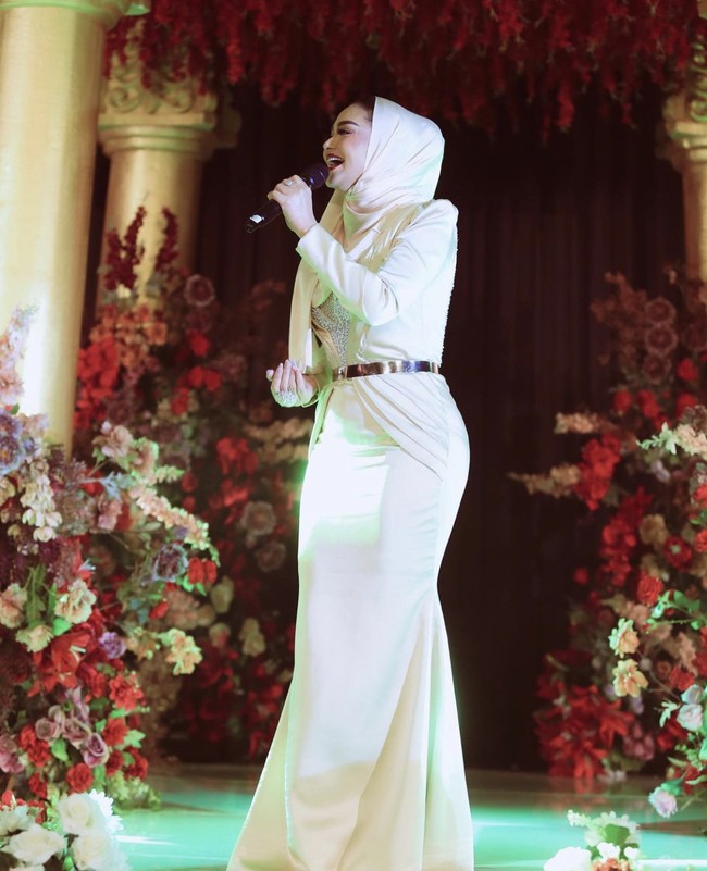 Tampil memakai kerudung di Aceh, pelantun lagu Menghitung Hari memadukan gayanya dengan dress panjang warna ivory dilengkapi dengan belt warna silver.  Foto: Dok. Instagram @krisdayantilemos.