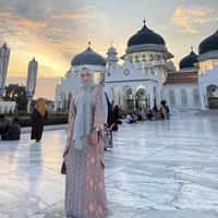 Wanita yang lahir 24 Maret 1975 di Batu, Jawa Timur ini mengunggah foto OOTD menggunakan kaftan panjang bahan satin motif print songket saat berpose di Masjid Raya Baiturrahman, Banda Aceh.  Foto: Dok. Instagram @krisdayantilemos.