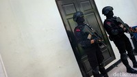 Kedua personel Brimob berseragam lengkap dan membawa senjata laras panjang.  