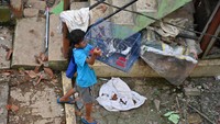 Seorang anak membawa kucing yang berhasil diselamatkan dari rumah yang rusak akibat gempa.  