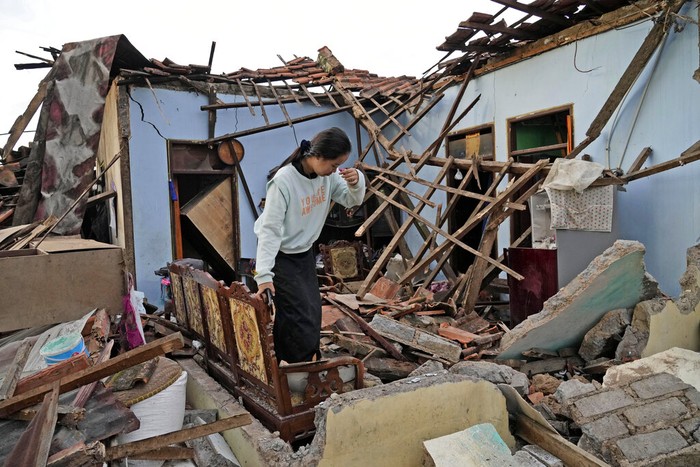 A woman reacts as she inspects her house that was badly damaged during an earthquake in Cianjur, West Java, Indonesia Tuesday, Nov. 22, 2022. The earthquake has toppled buildings on Indonesias densely populated main island, killing a number of people and injuring hundreds. (AP Photo/Tatan Syuflana)