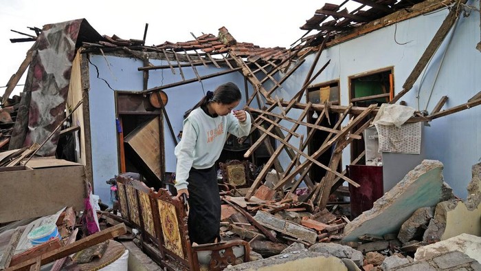 A woman reacts as she inspects her house that was badly damaged during an earthquake in Cianjur, West Java, Indonesia Tuesday, Nov. 22, 2022. The earthquake has toppled buildings on Indonesia's densely populated main island, killing a number of people and injuring hundreds. (AP Photo/Tatan Syuflana)