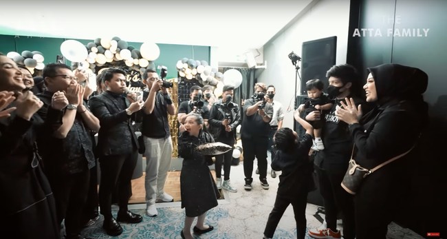 Awalnya Aurel meminta Atta untuk menutup mata terlebih dahulu. Dan ketika masuk ke lokasi pesta kejutan ulang tahun, barulah lampu dinyalakan dan terlihat para anggota keluarga sudah menantikan kehadiran Atta dan Aurel. Atta yang sedang menggendong Ameena pun tampak terkejut. Foto: YouTube/AH