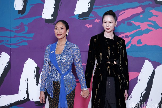 Duo Happy Salma dan Laura Basuki dari film Nana tampil bersama di karpet merah FFI 2022. Kebaya klasik biru dengan aksen selendang karya Biyan menjadi andalan Happy, sementara Laura bersolek dengan busana gelap dari Tangan Official. (Foto: Palevi S/detikFoto)