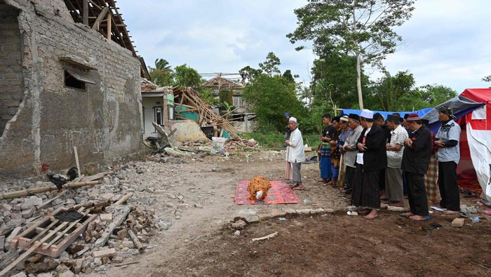 Korban Gempa Cianjur Gelar Salat Jenazah di Antara Reruntuhan TOPSHOT - Relatives offer prayers during the funeral of 48-year-old victim Husein, who was killed while building a house, at a village near Cianjur on November 22, 2022, following a 5.6-magnitude earthquake. - The death toll from an earthquake on Indonesia's main island of Java jumped to 268 on November 22, as rescuers searched for survivors in the rubble and relatives started to bury their loved ones. (Photo by ADEK BERRY / AFP) (Photo by ADEK BERRY/AFP via Getty Images)