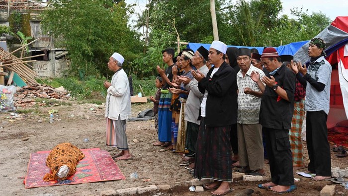 TOPSHOT - Relatives offer prayers during the funeral of 48-year-old victim Husein, who was killed while building a house, at a village near Cianjur on November 22, 2022, following a 5.6-magnitude earthquake. - The death toll from an earthquake on Indonesia's main island of Java jumped to 268 on November 22, as rescuers searched for survivors in the rubble and relatives started to bury their loved ones. (Photo by ADEK BERRY / AFP) (Photo by ADEK BERRY/AFP via Getty Images)