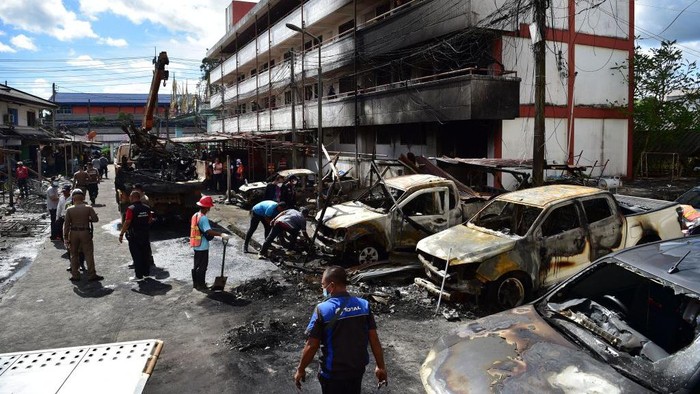 Sisa-sisa Setelah Bom Mobil Meledak di Kompleks Polisi Thailand Municipal workers clear the street a day after a car bomb exploded outside a police accommodation, in Muang district in Thailand's southern province of Narathiwat on November 23, 2022. - One person died and more than two dozen were injured in southern Thailand after a car bomb exploded outside police accommodation on November 22, 2022. (Photo by Madaree TOHLALA / AFP) (Photo by MADAREE TOHLALA/AFP via Getty Images)
