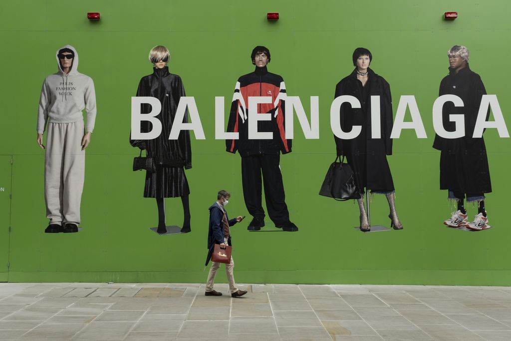 People interact with large scale action figures wearing fashionable clothing against a huge green hoarding which covers the Balenciaga store during a refit in the upmarket area on Bond Street on 25th May 2021 in London, United Kingdom. These high end brands are seen next to each other on a very ordinary wall. Bond Street is one of the principal streets in the West End shopping district and is very upmarket. It has been a fashionable shopping street since the 18th century. The rich and wealthy shop here mostly for high end fashion and jewellery. (photo by Mike Kemp/In Pictures via Getty Images)