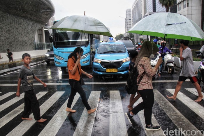Para ojek payung menawarkan jasa saat hujan deras di kawasan Bundaran HI, Jalan MH Thamrin Jakarta