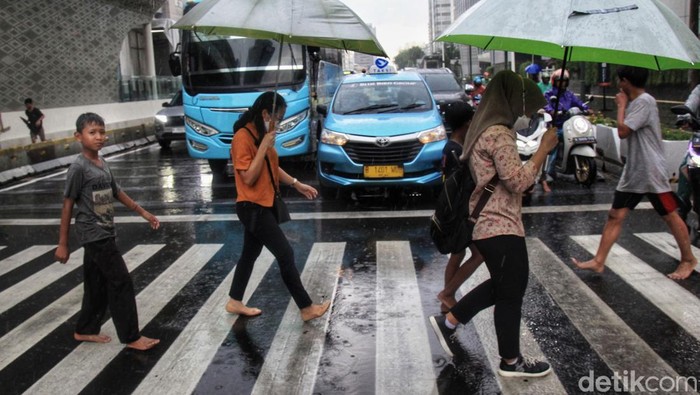 Para ojek payung menawarkan jasa saat hujan deras di kawasan Bundaran HI, Jalan MH Thamrin Jakarta