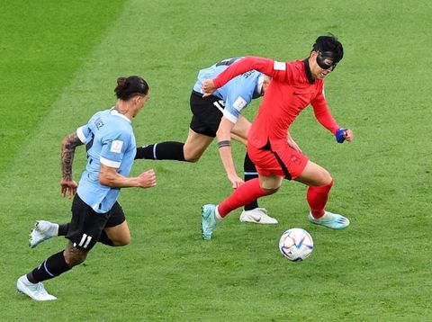 AL RAYYAN, QATAR - NOVEMBER 24:   Heung-min Son of Korea Republic battles for the ball with Martin Caceres of Uruguay during  the FIFA World Cup Qatar 2022 Group H match between Uruguay and Korea Republic at Education City Stadium on November 24, 2022 in Al Rayyan, Qatar. (Photo by Chris Brunskill/Fantasista/Getty Images)