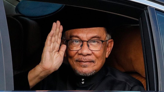 Malaysias newly appointed Prime Minister Anwar Ibrahim waves from his car as he arrives to take part in the swearing-in ceremony at the National Palace in Kuala Lumpur on November 24, 2022. (Photo by FAZRY ISMAIL / POOL / AFP)