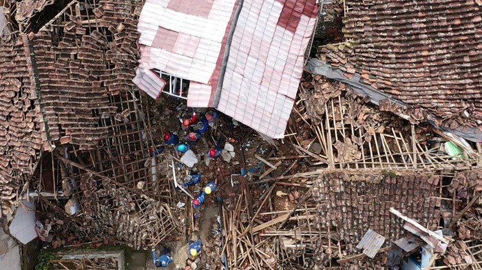 An aerial view shows rescue personnel working to rescue a child from the rubble of a collapsed house at Cugenang in Cianjur, West Java on November 24, 2022, following a 5.6-magnitude earthquake on November 21. - Survivors of an Indonesian earthquake that killed at least 271 people, many of them children, appealed for food and water November 23 as heavy rain and aftershocks hampered rescue efforts among the rubble of devastated villages. (Photo by ADEK BERRY / AFP) (Photo by ADEK BERRY/AFP via Getty Images)