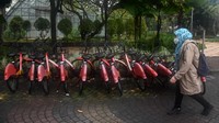 Pekerja melintas di dekat sepeda Gowes yang terparkir di kawasan Taman Menteng, Jakarta, Rabu (23/11/2022).