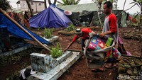 Di samping tenda-tenda pengungsian itu terdapat kuburan bernisan hingga kuburan baru.