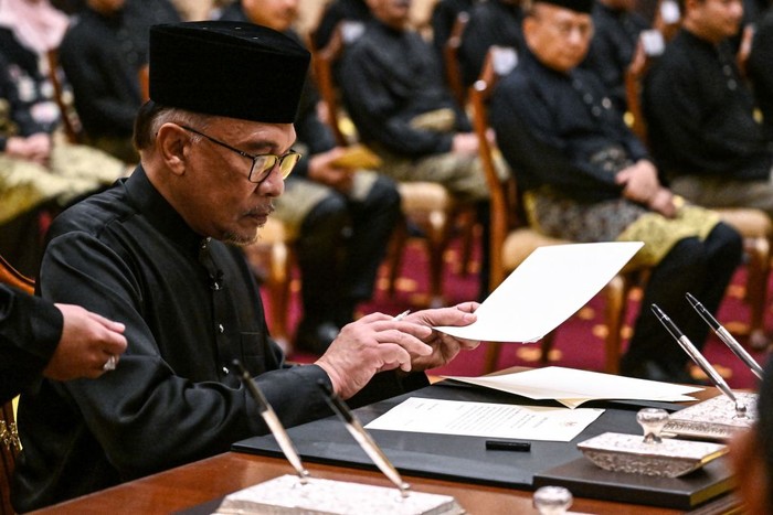 Malaysias newly appointed Prime Minister Anwar Ibrahim signs documents after taking the oath during the swearing-in ceremony at the National Palace in Kuala Lumpur on November 24, 2022. (Photo by MOHD RASFAN / POOL / AFP) (Photo by MOHD RASFAN/POOL/AFP via Getty Images)