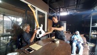 Sri Hadi Waluyo menyerahkan gitar kepada pelanggannya. Dia membutuhkan waktu hingga enam pekan untuk menyelesaikan pembuatan pesanan gitar custom. Foto: Anggah/detikJateng