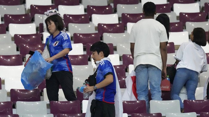 Japan supporters clean the stands at the end of the World Cup group E soccer match between Germany and Japan, at the Khalifa International Stadium in Doha, Qatar, Wednesday, Nov. 23, 2022. Japan won 2-1.(AP Photo/Eugene Hoshiko)