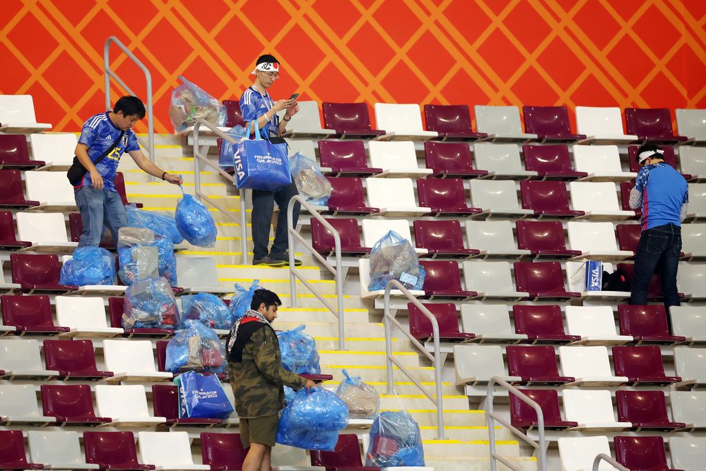 DOHA, QATAR - NOVEMBER 23: Japanese fans clear rubbish from the stands during the FIFA World Cup Qatar 2022 Group E match between Germany and Japan at Khalifa International Stadium on November 23, 2022 in Doha, Qatar. (Photo by Alex Grimm/Getty Images)