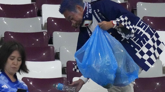 Salut! Suporter Jepang Punguti Sampah di Stadion Piala Dunia Japan supporters clean the stands at the end of the World Cup group E soccer match between Germany and Japan, at the Khalifa International Stadium in Doha, Qatar, Wednesday, Nov. 23, 2022. Japan won 2-1.(AP Photo/Eugene Hoshiko)