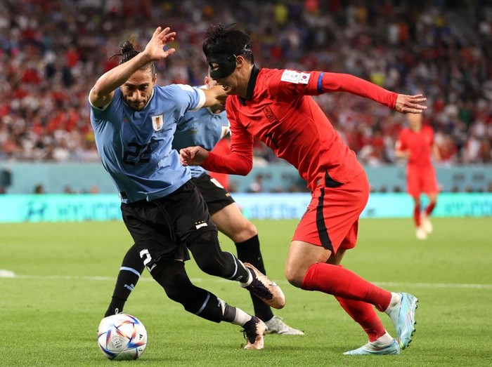 AL RAYYAN, QATAR - NOVEMBER 24: Heungmin Son of Korea Republic battles for possession with Martin Caceres of Uruguay  during the FIFA World Cup Qatar 2022 Group H match between Uruguay and Korea Republic at Education City Stadium on November 24, 2022 in Al Rayyan, Qatar. (Photo by Ryan Pierse/Getty Images)