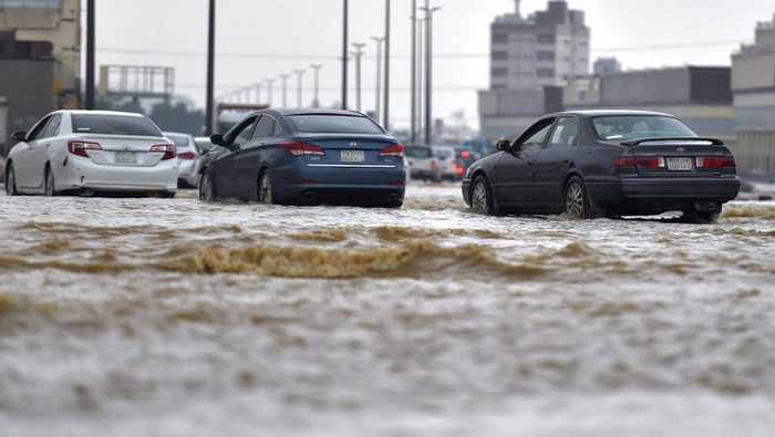 Cars drive through a flooded street following heavy rains in the Saudi coastal city of Jeddah on November 24, 2022, which delayed flights, forced school suspensions and closed the road to Mecca, Islams holiest city. - Jeddah, a city of roughly four million people positioned on the Red Sea, is often referred to as the 