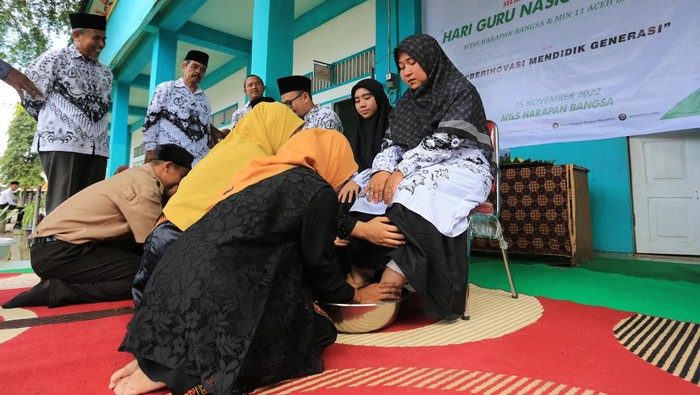 Sejumlah siswa-siswi membasuh kaki guru sebagai tanda penghormatan seusai upacara peringatan Hari Guru Nasional (HGN) 2022 di Madrasah Tsanawiyah Swasta (MTsS) Harapan Bangsa dan Madrasah Ibtidayah Negeri 11 Aceh Barat Desa Kuta Padang, Johan Pahlawan, Aceh Barat, Aceh, Jumat (25/11/2022). Rangkaian peringatan hari guru nasional di Aceh dikemas dengan aksi berbakti kepada guru seperti membasuh kaki guru dan menyuapkan nasi kepada guru dengan tujuan untuk menanamkan rasa hormat kepada guru yang telah memberikan bimbingan serta ilmu pengetahuan dalam memajukan dan meningkatkan pendidikan di Indonesia. ANTARA FOTO/Syifa Yulinnas/aww.