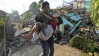 Anak itu digendong karena mengalami luka di kedua kakinya. AP Photo/Tatan Syuflana.