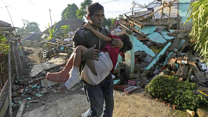 Momen Ayah Gendong Anak yang Luka Akibat Gempa Cianjur Seorang anak dalam kondisi luka dievakuasi ayahnya menuju pengungsian di Cianjur. Anak itu dievakuasi dengan cara digendong melintasi puing-puing bangunan.